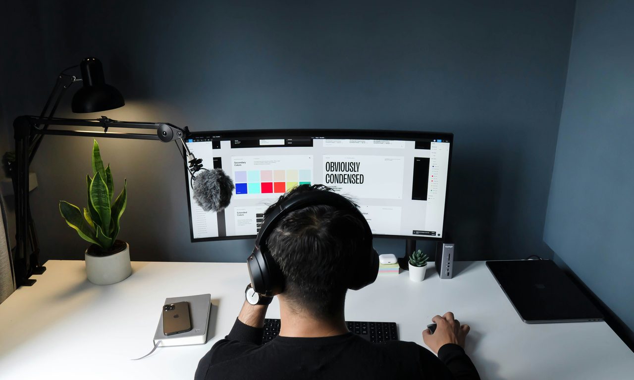 Designer am Schreibtisch vor einem Bildschirm mit einem Farb- und Schriftkonzept