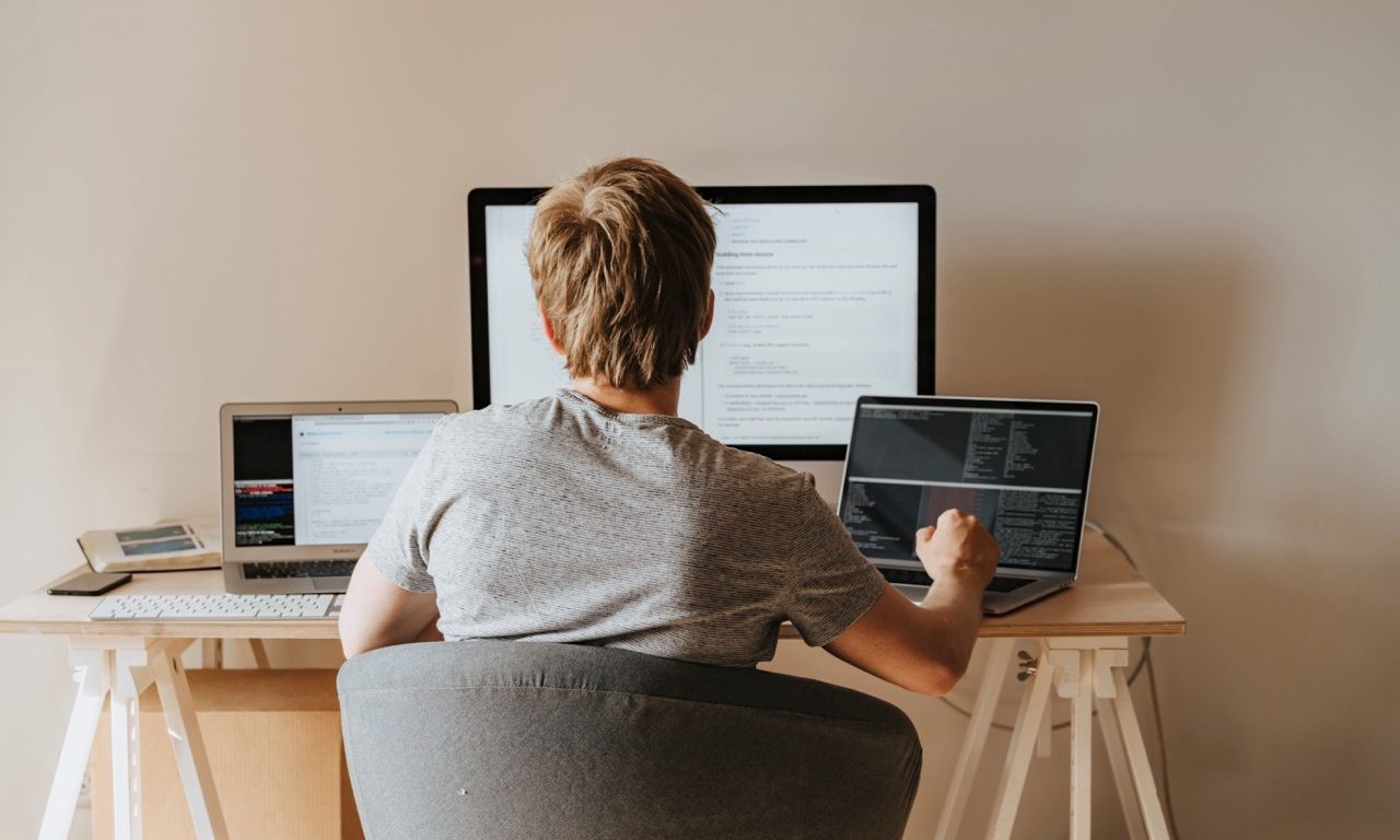 Entwickler arbeitet konzentriert an zwei Bildschirmen mit Code